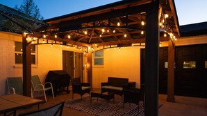 Eine Außenpatio-Terrasse mit überdachter Sitzecke, Grill und Lichterketten.