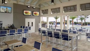 Un grand espace extérieur aménagé avec des tables et des chaises, un comptoir et une vue sur la plage.
