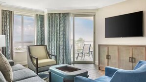 Une chambre d’hôtel équipée d’un canapé, d’un fauteuil et d’un téléviseur à écran plat fixé au mur.