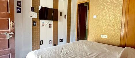 A hotel room with a bed, a ceiling fan, a door, and a wall with a patterned design.