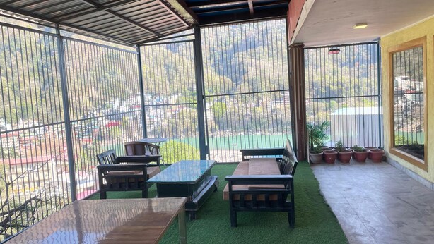 A covered outdoor seating area with a view of a mountainous landscape. - Hotel Elevate Nirvana (Rishikesh)