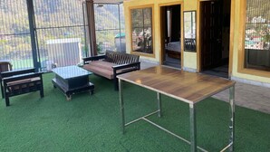 A room with a green artificial turf floor, a wooden table, a sofa, and a bed. - Hotel Elevate Nirvana (Rishikesh)