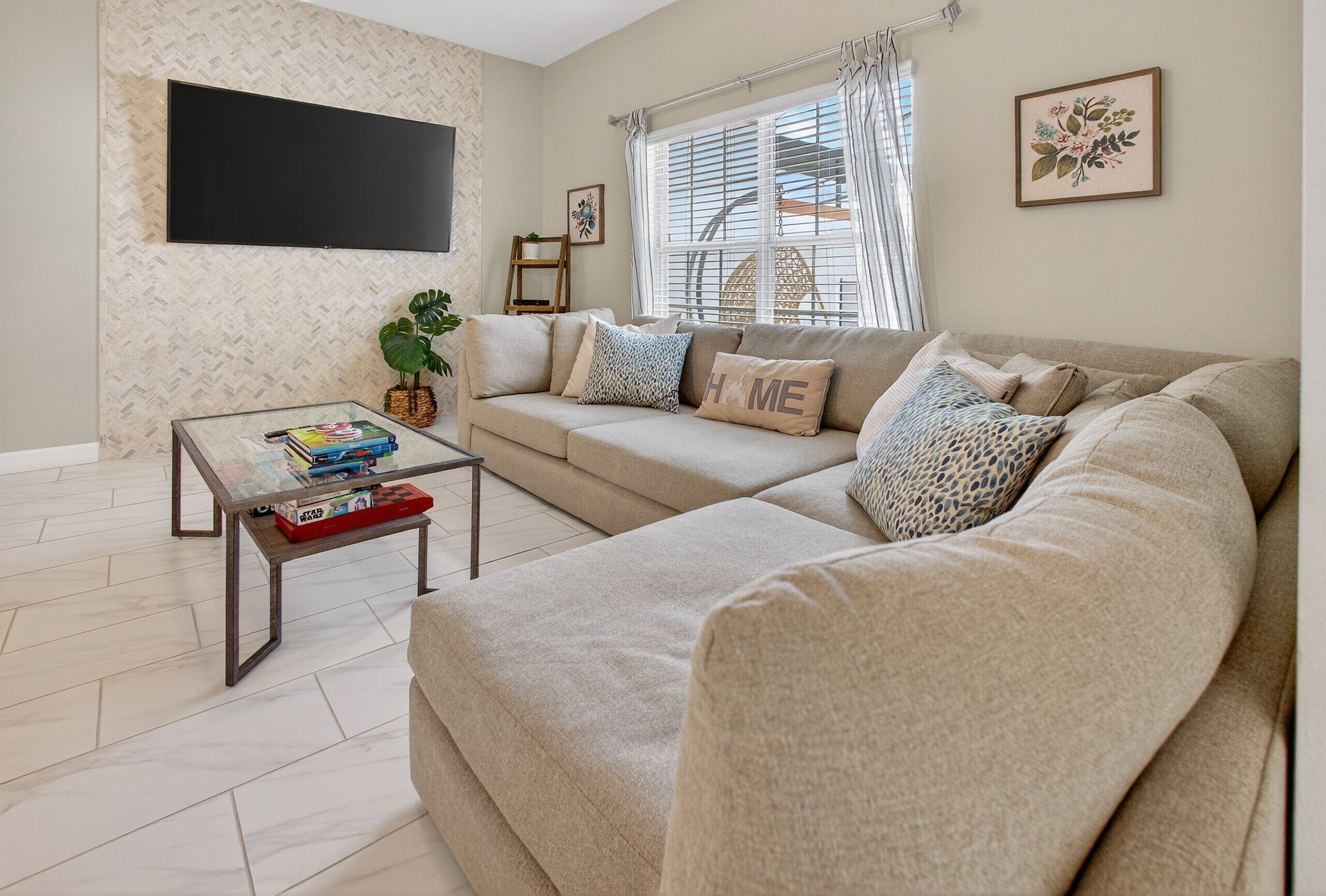 A living room with a sofa, a coffee table, a TV, and a window with curtains.