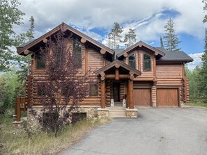 A log cabin with a stone foundation, a front porch, and a garage.