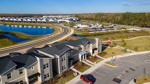 A modern building complex with a parking lot and a body of water. - Last Minute Disney Getaway! Private Pool & Themed Bedrooms. Book Now! #165355 (Orlando)