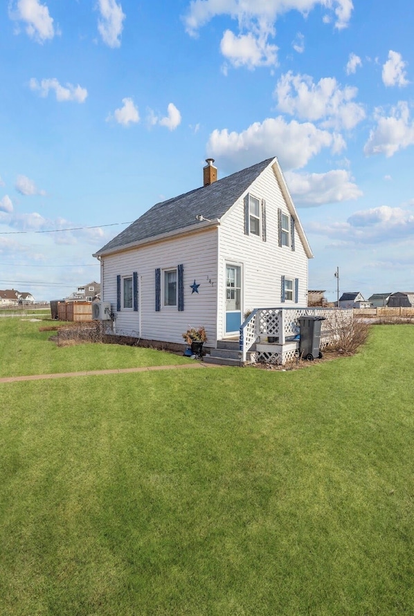 A white house with a blue star, a porch, and a grassy yard.