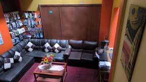 Una habitación con un sofá modular, una mesa de centro con un arreglo floral, una estantería y un escritorio con una computadora.