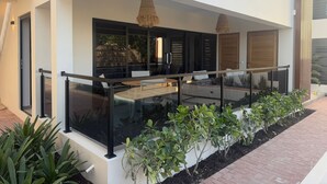 Ein modernes Gebäude mit einem Glasbalkon, einer Holztür und einem kleinen Garten.