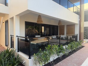 A modern building with a glass balcony, a wooden door, and a small garden area. - Luxury apartment, including pool, 6 minutes from Mambo Beach. (Willemstad)