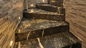 Una escalera con un muro de piedra a un lado y un ventanal en la parte superior.