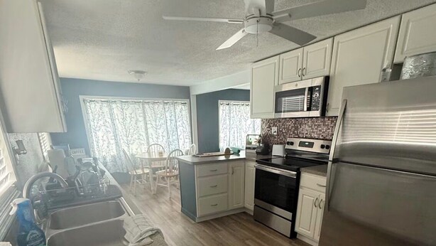 A kitchen with a microwave, stove, refrigerator, and ceiling fan. - Cozy 2-bedroom house in peaceful Hudson on a canal (Hudson)
