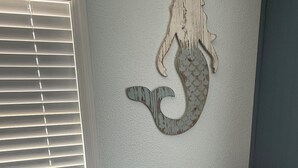 Une pièce décorée d’une fresque représentant une sirène, avec un coin café et un haut-parleur bleu.