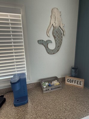 Une pièce décorée d’une fresque représentant une sirène, avec un coin café et un haut-parleur bleu.