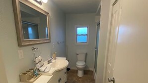 A bathroom with a vanity, mirror, toilet, and a window. - Cozy 2-bedroom house in peaceful Hudson on a canal (Hudson)