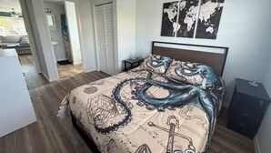 A bedroom with a bed, a ceiling fan, a world map on the wall, and a view of the outside. - Cozy 2-bedroom house in peaceful Hudson on a canal (Hudson)