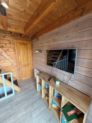 Ein Holzinnenraum mit an der Wand montiertem Fernseher, Holzböden und einer Treppe.