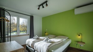 Ein Schlafzimmer mit einem Bett, Nachttischen, einem Schreibtisch, einem Fenster mit Vorhängen und einer grünen Wand.