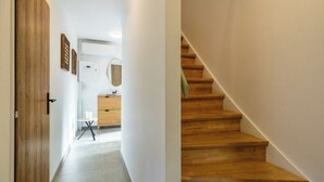 Ein Flur mit Holztür, einem kleinen Tisch mit Stuhl, einem Holzschrank und einer Treppe mit Holzbodenstufen.