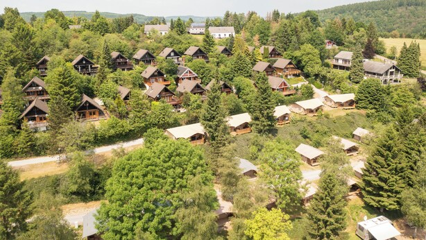 Um conjunto de cabanas rodeado por uma floresta densa, com um céu claro acima.