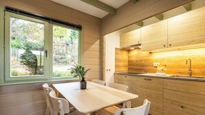 Uma cozinha moderna com armários de madeira, bancada e janela com vista para árvores.