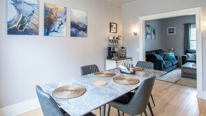 Ruokailutila, jossa on marmoripöytä, harmaat tuolit ja punotut alustat.