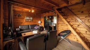 Un interior de madera con sofá, sillas, una mesa de comedor y una pequeña cocina.