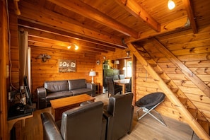 L’intérieur d’un chalet accueillant, avec un plafond en bois, un canapé, une table à manger et une chaise.
