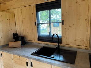 A kitchen with wooden cabinets, a black sink, and a window with a view of trees. - Cape Town is a cottage with plenty of space and a terrace, designed for families or groups of friends. With 2 bedrooms, this cottage can accommodate between 4 people. (Dochamps)