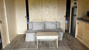 Un interior de madera con un sofá gris, una mesa de madera y una zona de cocina.