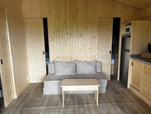 A wooden interior with a grey sofa, a wooden table, and a kitchen area. - Cape Town is a cottage with plenty of space and a terrace, designed for families or groups of friends. With 2 bedrooms, this cottage can accommodate between 4 people. (Dochamps)