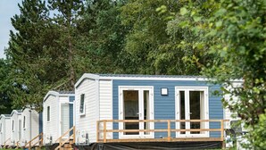 A row of mobile homes with a wooden deck and a small porch. - The Grande Large mobile home is a fully equipped, comfortable accommodation for 6 people, ideal in any season thanks to its three bedrooms, terrace, air conditioning, and central heating. (Dochamps)