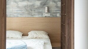 Quarto com cabeceira de madeira, cama com roupa de cama branca, tomada na parede e guarda-roupa de madeira.