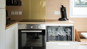 Uma cozinha moderna com forno embutido, máquina de café e uma janela grande.