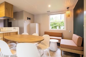 Una cocina moderna con electrodomésticos blancos, una mesa redonda de madera y sillas blancas.