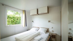 Quarto com uma cama de solteiro, janela com cortinas, mesas de cabeceira e armários embutidos.