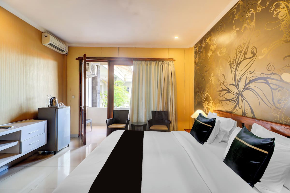 A hotel room with a bed, a desk, two chairs, a small table, and a view of the outdoors.
