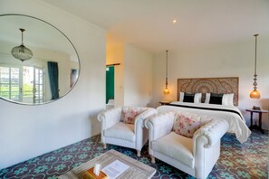 A hotel room with a bed, two armchairs, a round mirror, and a patterned floor. - Townhouse Oak Su's Cottage Near Legian Beach (Kuta)