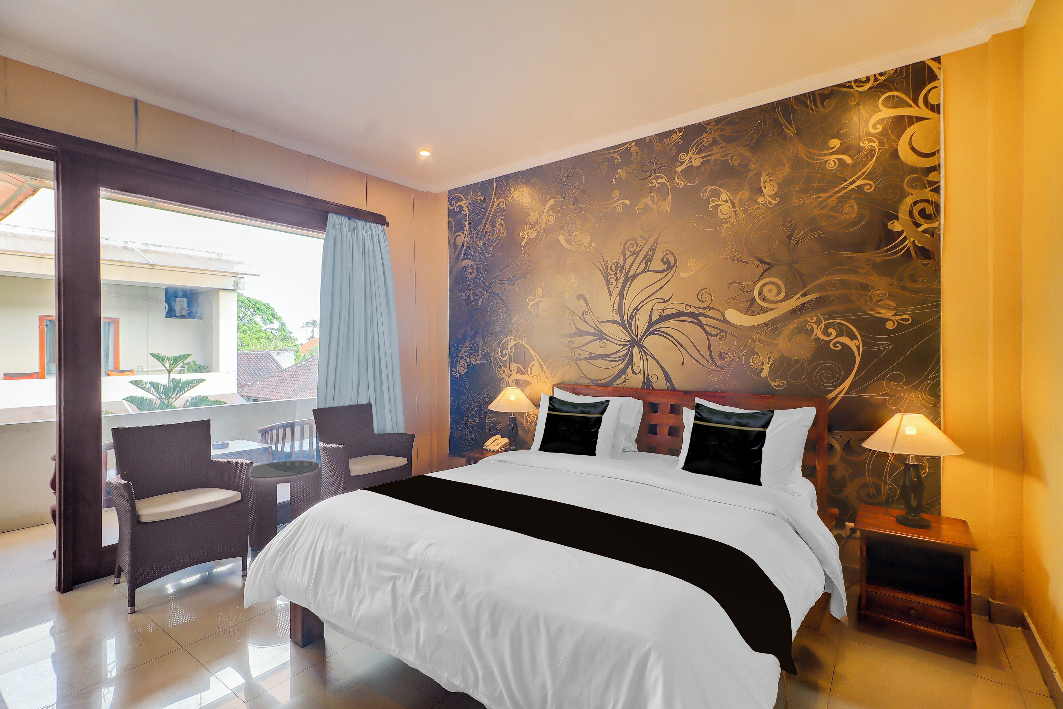 Una habitación de hotel con una cama grande, dos lámparas de noche, una mesita con sillas y vistas al exterior.