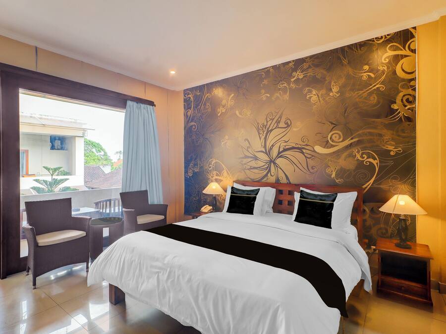 Una habitación de hotel con una cama grande, dos lámparas de noche, una mesita con sillas y vistas al exterior.
