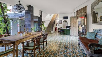 Amplia habitación con una mesa de comedor de madera, sillas, un sofá, una escalera y un suelo estampado.
