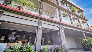 A multi-story hotel with balconies, potted plants, and a restaurant at the ground level. - Townhouse Oak Su's Cottage Near Legian Beach (Kuta)