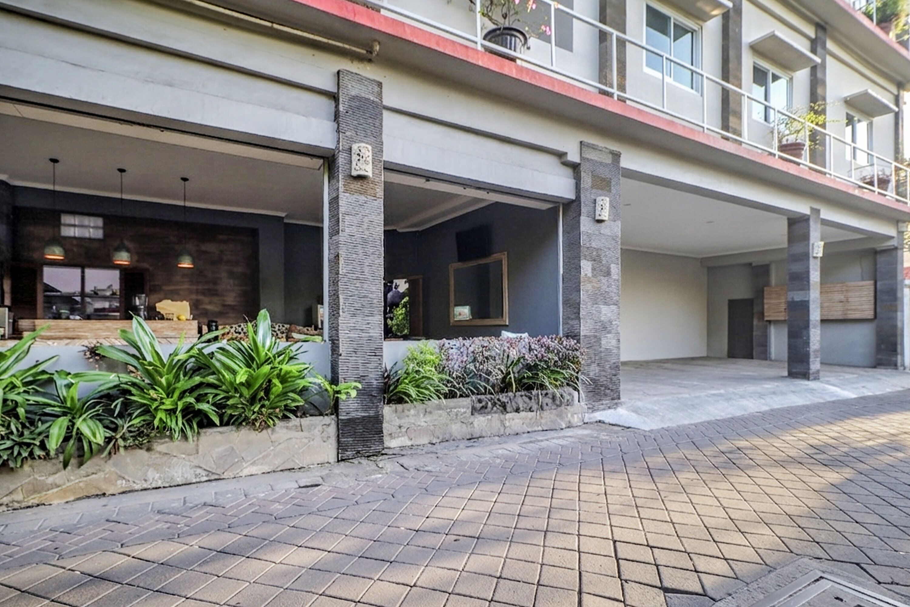 A modern building with a covered entrance, outdoor seating area, and potted plants.