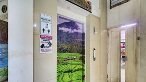 A hallway with a mural of a green landscape, a sign with health guidelines, and a door leading to another area. - Townhouse Oak Su's Cottage Near Legian Beach (Kuta)