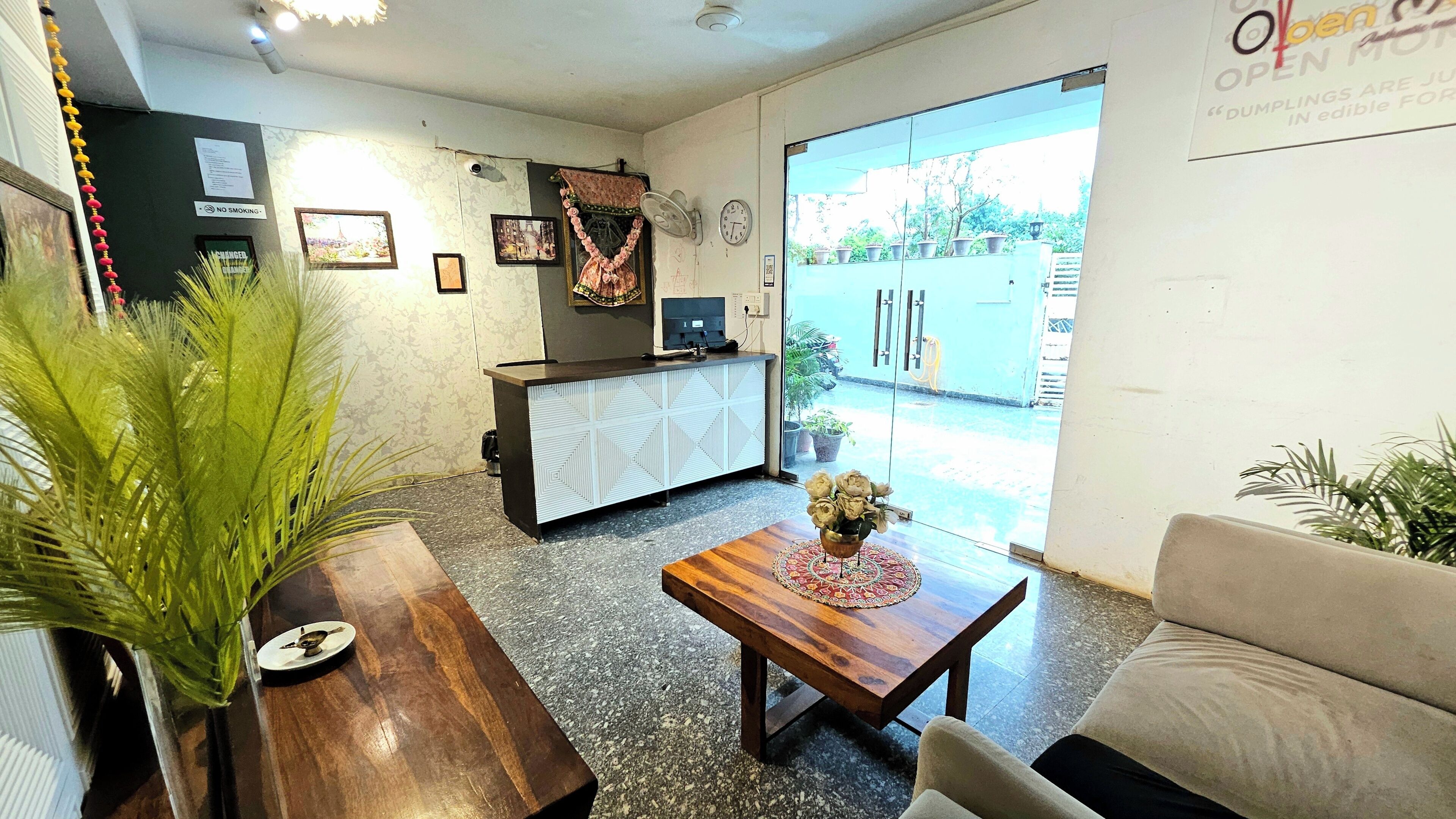 Un espace d’accueil comprenant un bureau en bois, un canapé, une table basse et une grande fenêtre donnant sur l’extérieur.