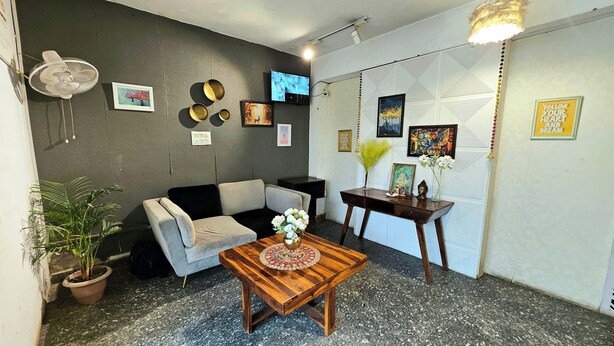 Un salon avec un canapé gris, une table basse en bois, un téléviseur et divers éléments de décoration murale.