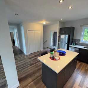 A modern kitchen with a central island, dark cabinetry, and a view of the outdoors. - Pool Table, Private Beach | Breakfast Included (Labelle)