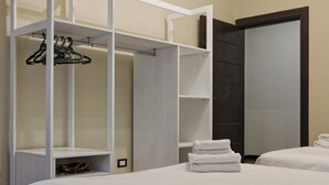 Quarto de hotel com beliche, guarda-roupa com espaço para pendurar roupas e um espelho grande.