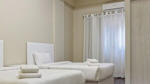 Quarto de hotel com duas camas, um ventilador de teto e vista para o exterior.