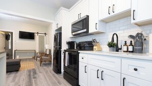 A modern kitchen with white cabinets, a black refrigerator, a microwave, and a stove. - Crest 2 Coastal Stay, 1st fl, AC, KB, Free Parking (Wildwood Crest)