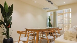 A dining area with a round table, wooden chairs, a potted plant, and a sofa. - VESTA  - Luxury APT - 4BR - New Cairo (II) (New Cairo City)